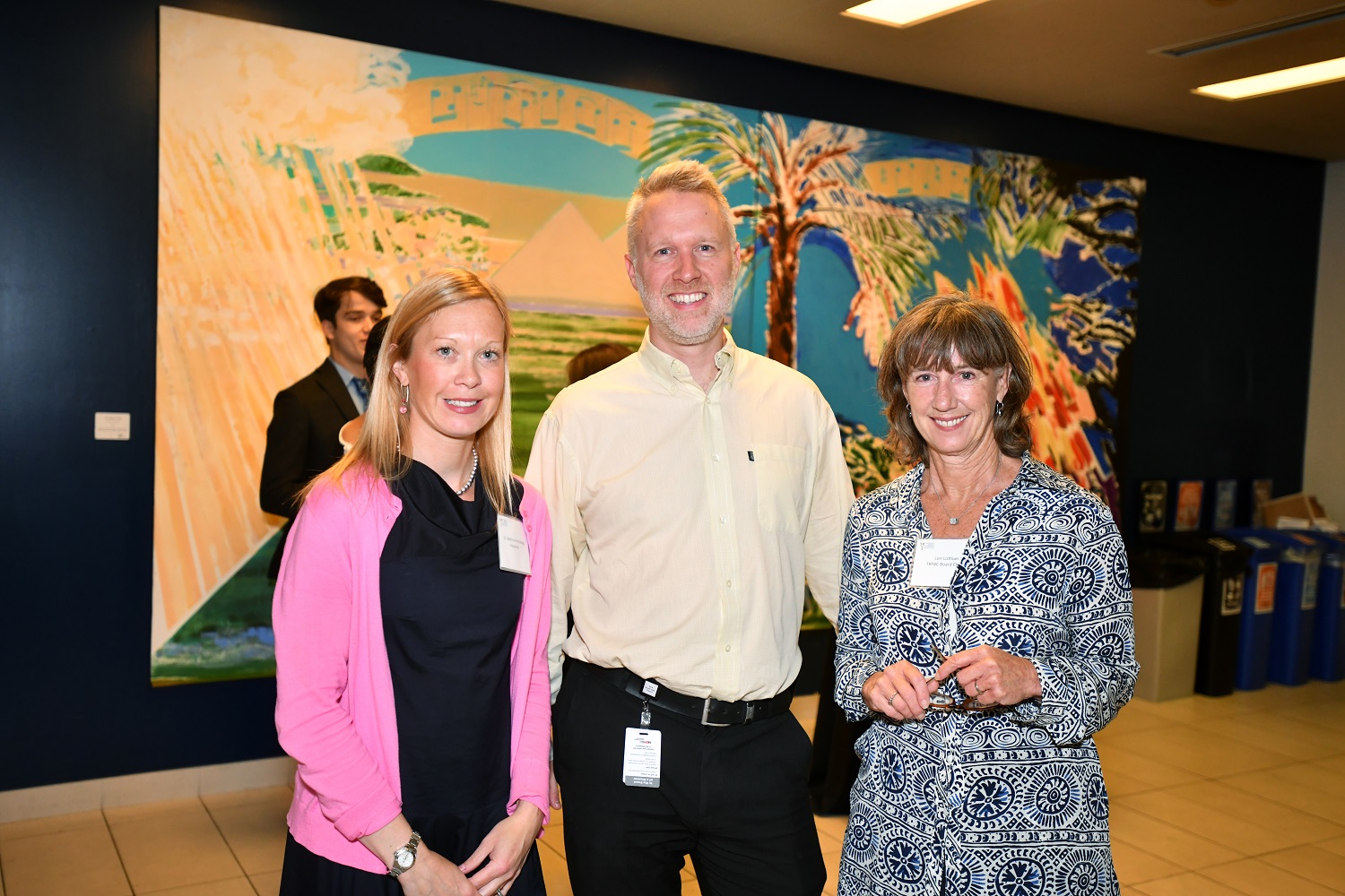 Three smiling people - two women and one man - wearing name badges