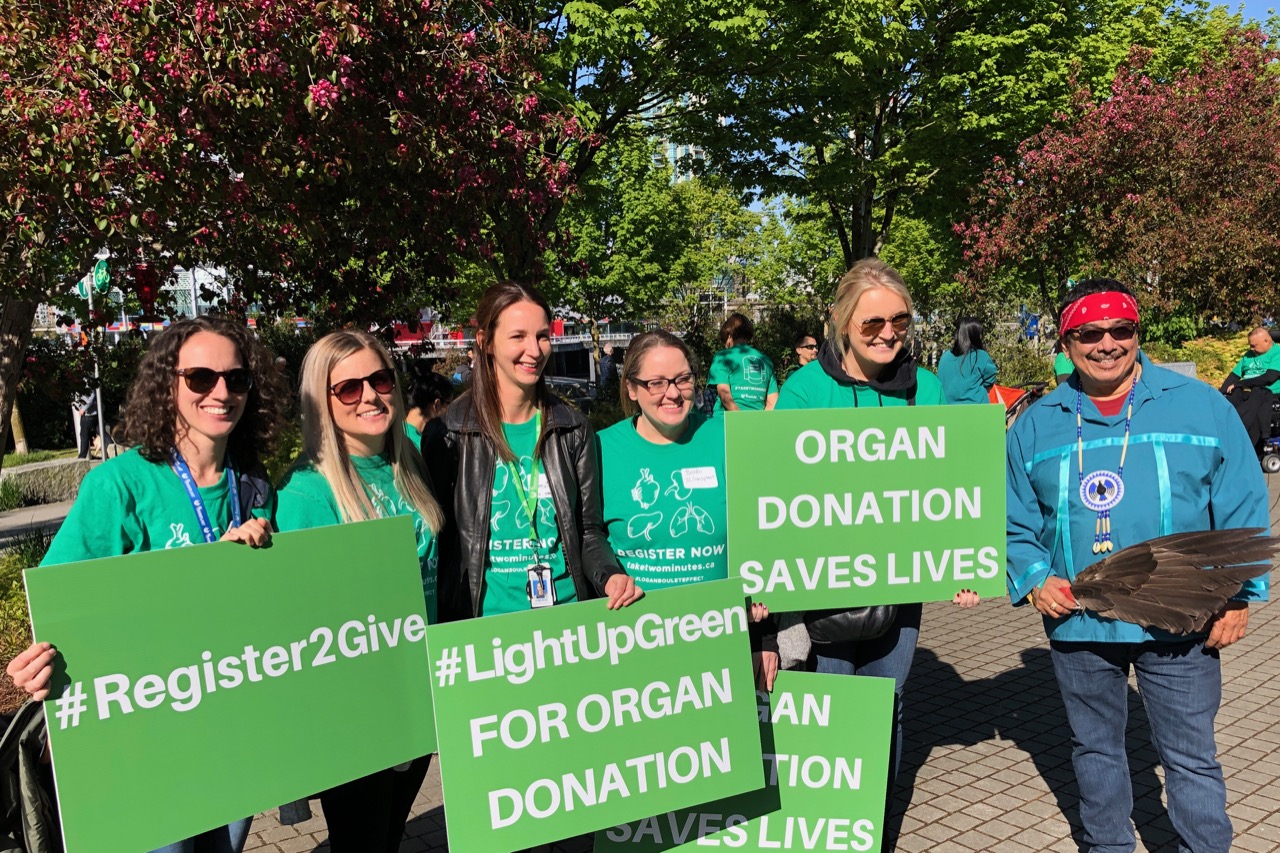 Group of people holding green signs encouraging organ donation